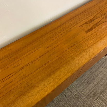 Close-up of a wooden desk edge with a white surface and gray carpet in the background
