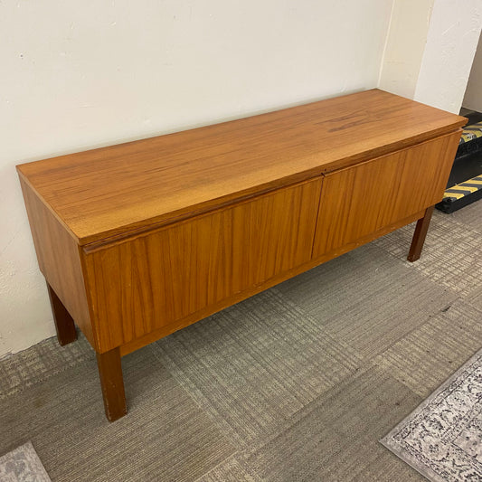 Wooden sideboard against a plain wall with a carpeted floor.