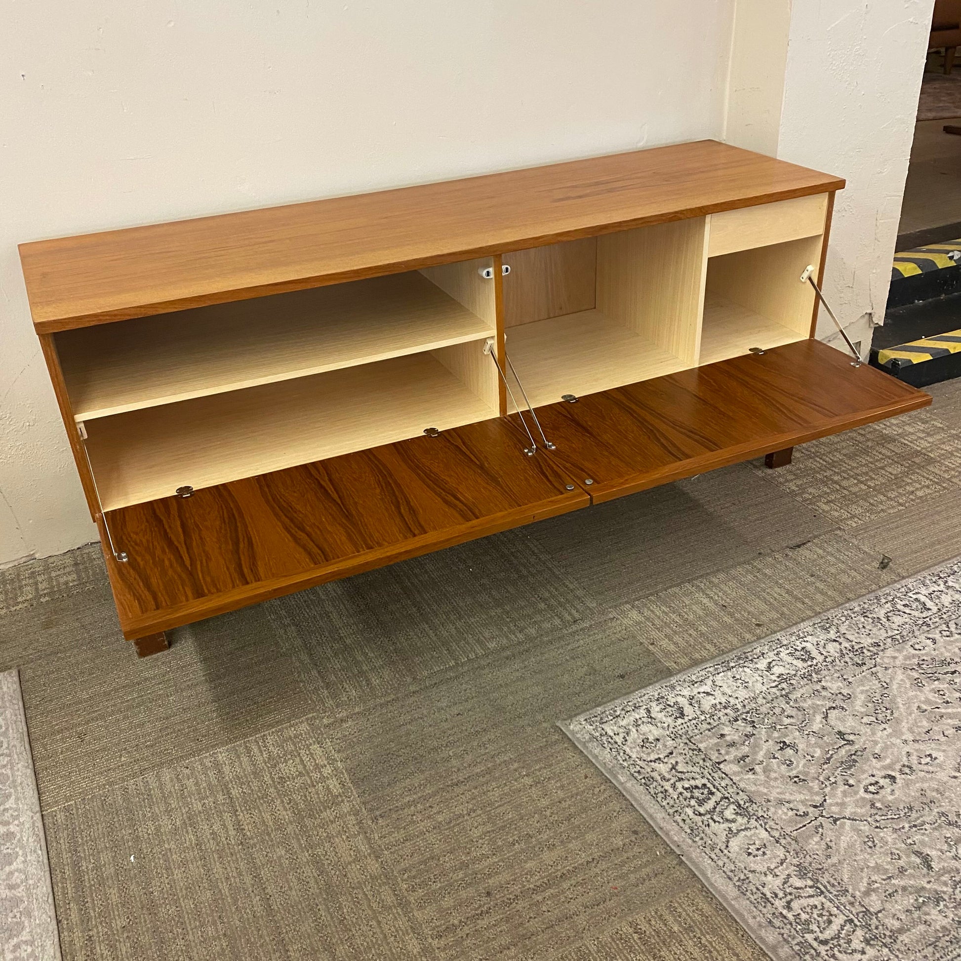 Wooden entertainment console with open doors on a carpeted floor.