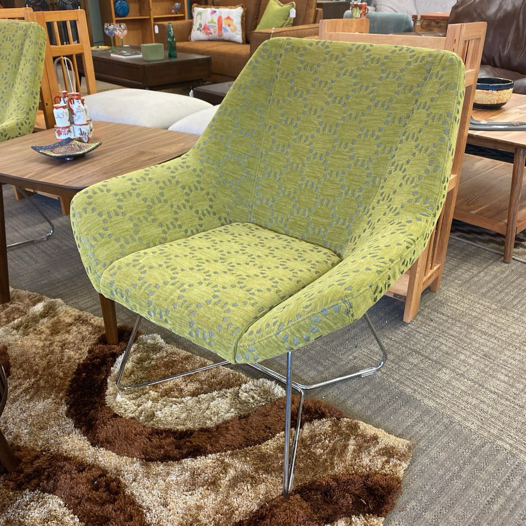 Green patterned chair in a living room setting with wooden furniture and a rug.