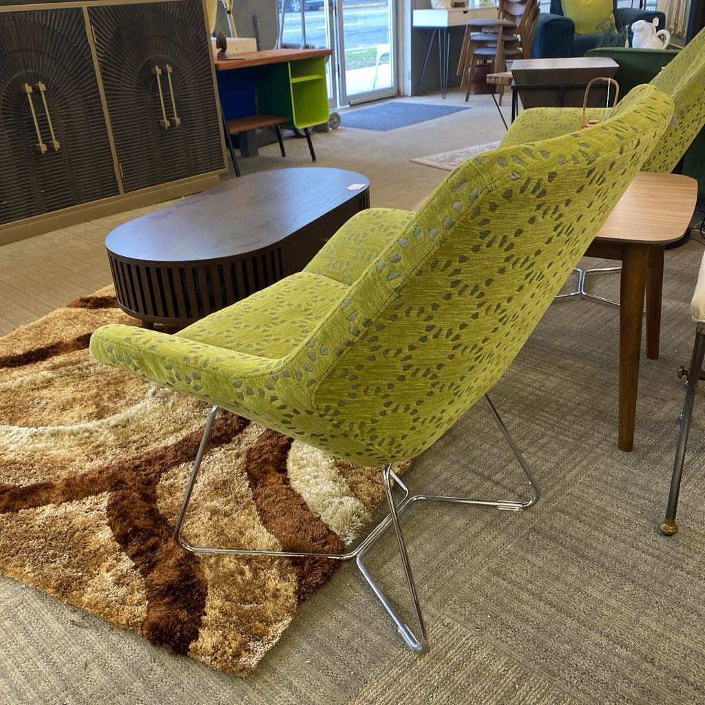 Green patterned chair in a room with a rug and furniture
