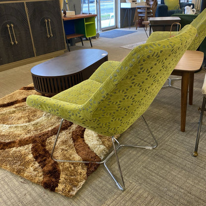 Green patterned chair in a room with a rug and furniture