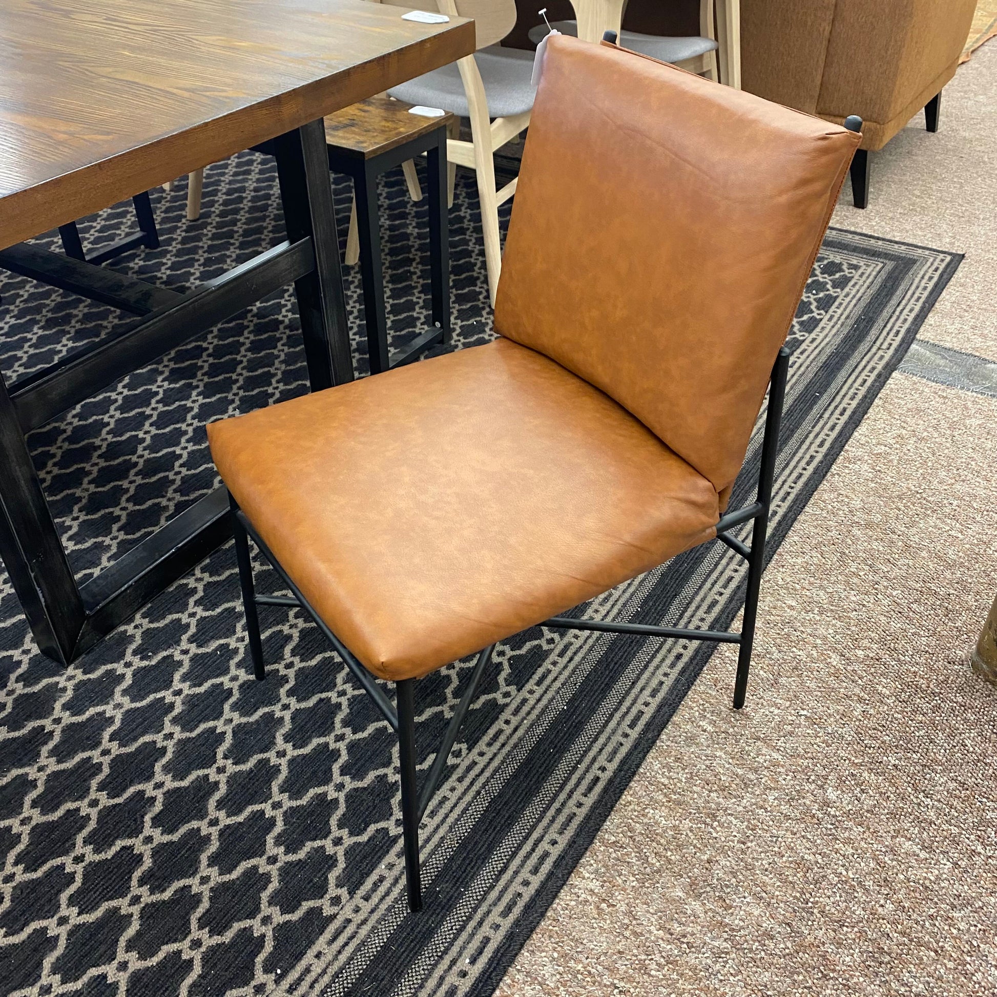 Brown leather chair on a patterned rug with a table in the background