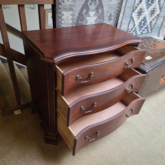 Wooden caskets stacked on a stand with a patterned rug in the background