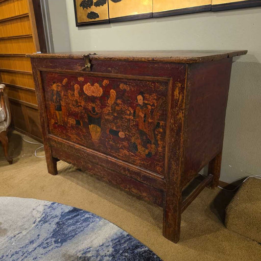 Vintage wooden chest with decorative paintwork in a room setting.