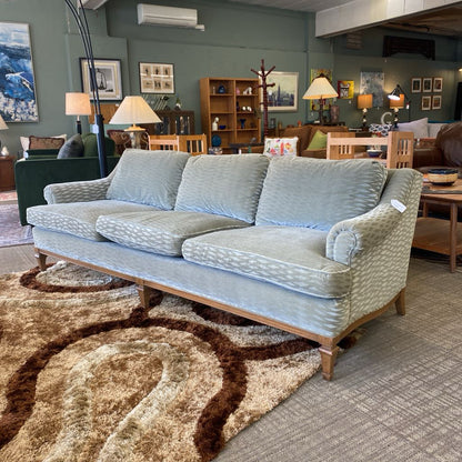 Light blue sofa in a living room setting with furniture and decor.