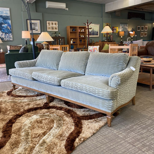 Light blue sofa in a living room setting with furniture and decor.