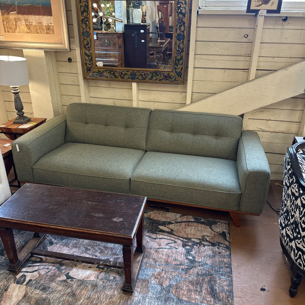 Green sofa in a room with wooden floor and furniture