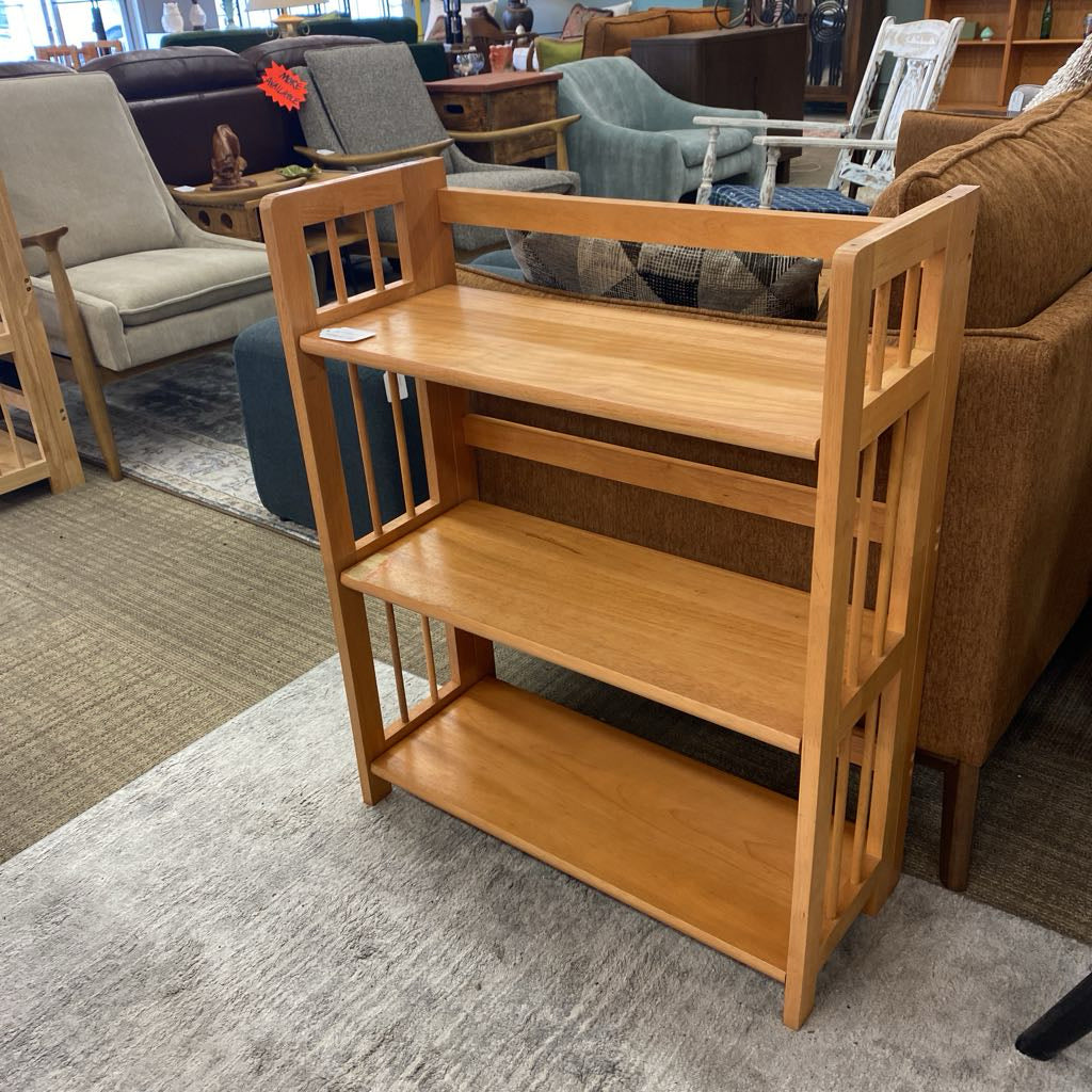 Wooden bookshelf in a furniture store with various seating options in the background.