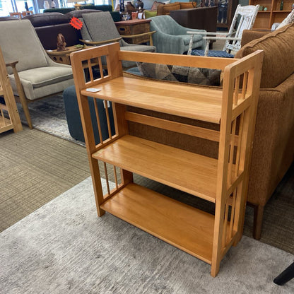 Wooden bookshelf in a furniture store with various seating options in the background.