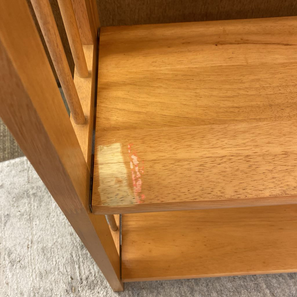 Close-up of a wooden shelf with a small red stain on a textured surface.