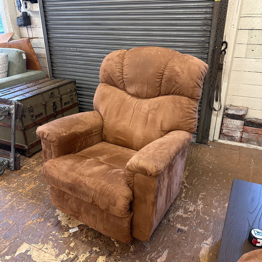 Brown recliner chair in a room with a metal shutter door and wooden floor.