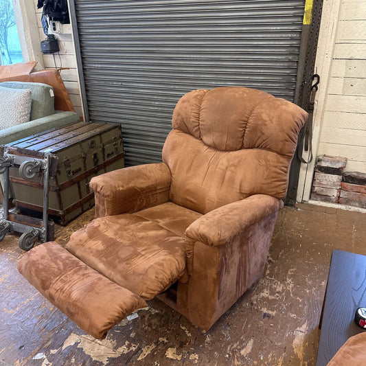 Brown recliner chair in a room with a metal shutter door.