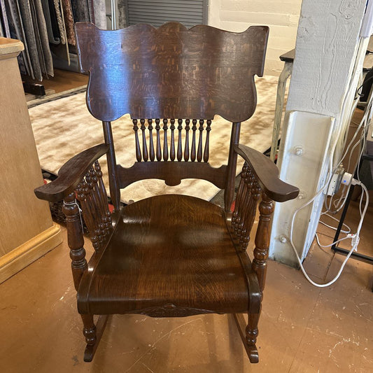 Wooden rocking chair in a room with visible cables and furniture.