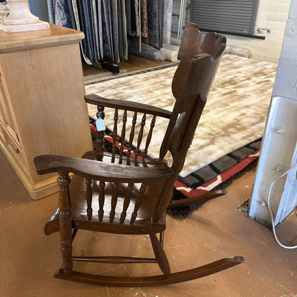 Wooden rocking chair in a store setting with clothes in the background