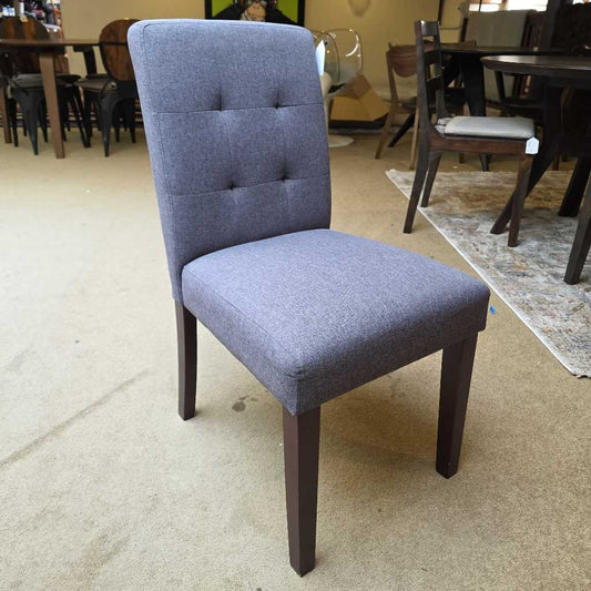 Gray upholstered chair with wooden legs on a beige floor.