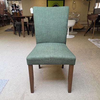 Green upholstered chair with wooden legs in a showroom setting