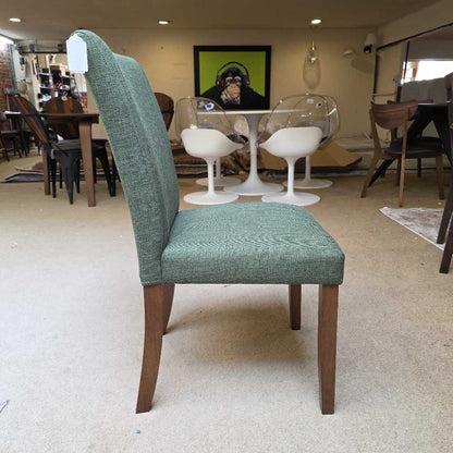 Green upholstered chair with wooden legs in a showroom setting