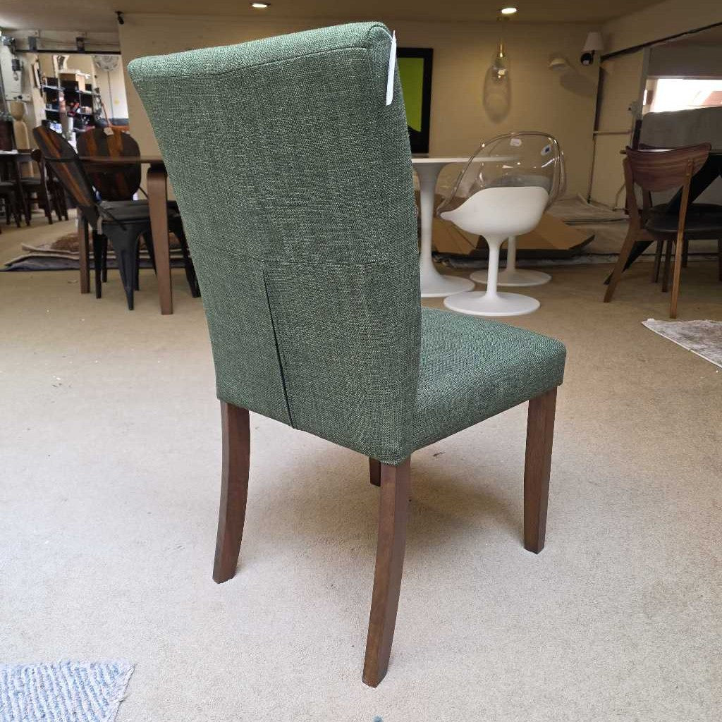 Green upholstered chair with wooden legs in a showroom setting