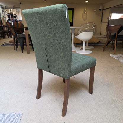 Green upholstered chair with wooden legs in a showroom setting