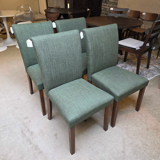 Green chairs with wooden legs stacked on a gray floor