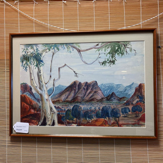 Framed artwork of a landscape with trees and mountains on a wall with blinds.