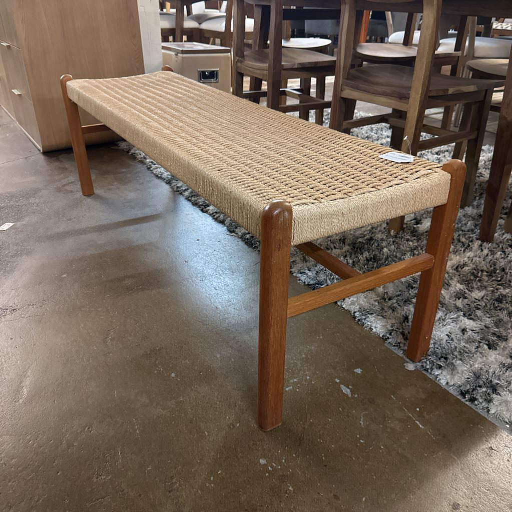 Wooden bench with woven seat in a showroom setting