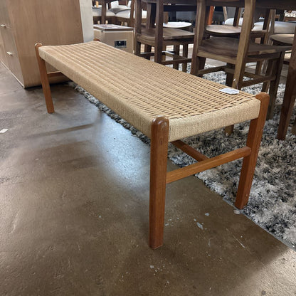 Wooden bench with woven seat in a showroom setting
