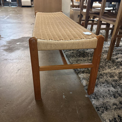 Wooden stool with woven seat on a concrete floor