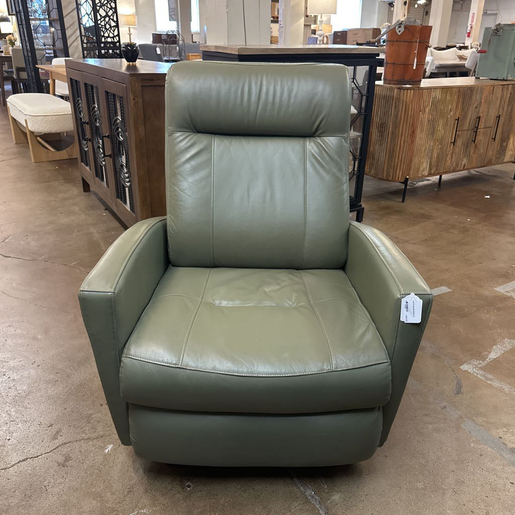 Green leather armchair in a showroom setting with other furniture.