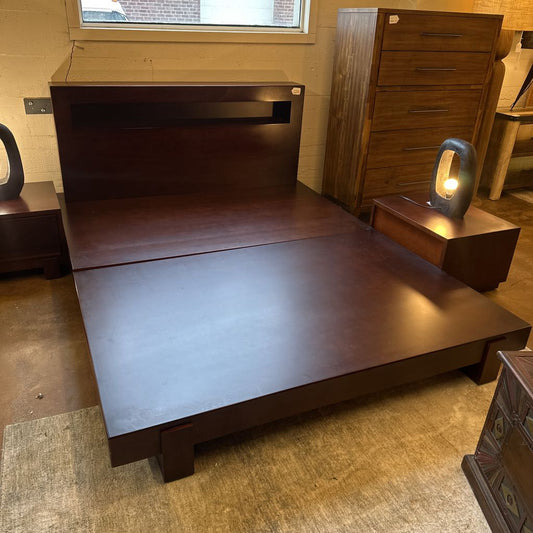 Wooden bed with a lamp on a nightstand in a room setting
