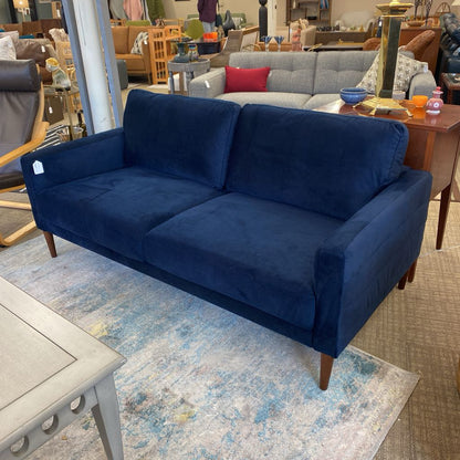 Blue sofa in a furniture store setting with other couches and decor items.