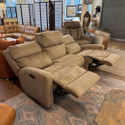 Beige recliner sofa in a room with various furniture and decor items.