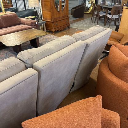 Gray sectional sofa and orange armchair in a room with various furniture pieces.