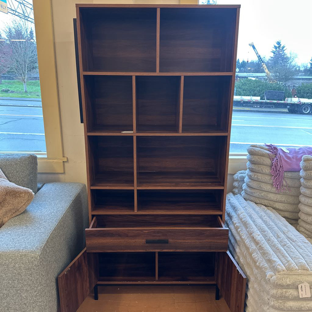 Wooden bookshelf with multiple compartments in a room with a window view.