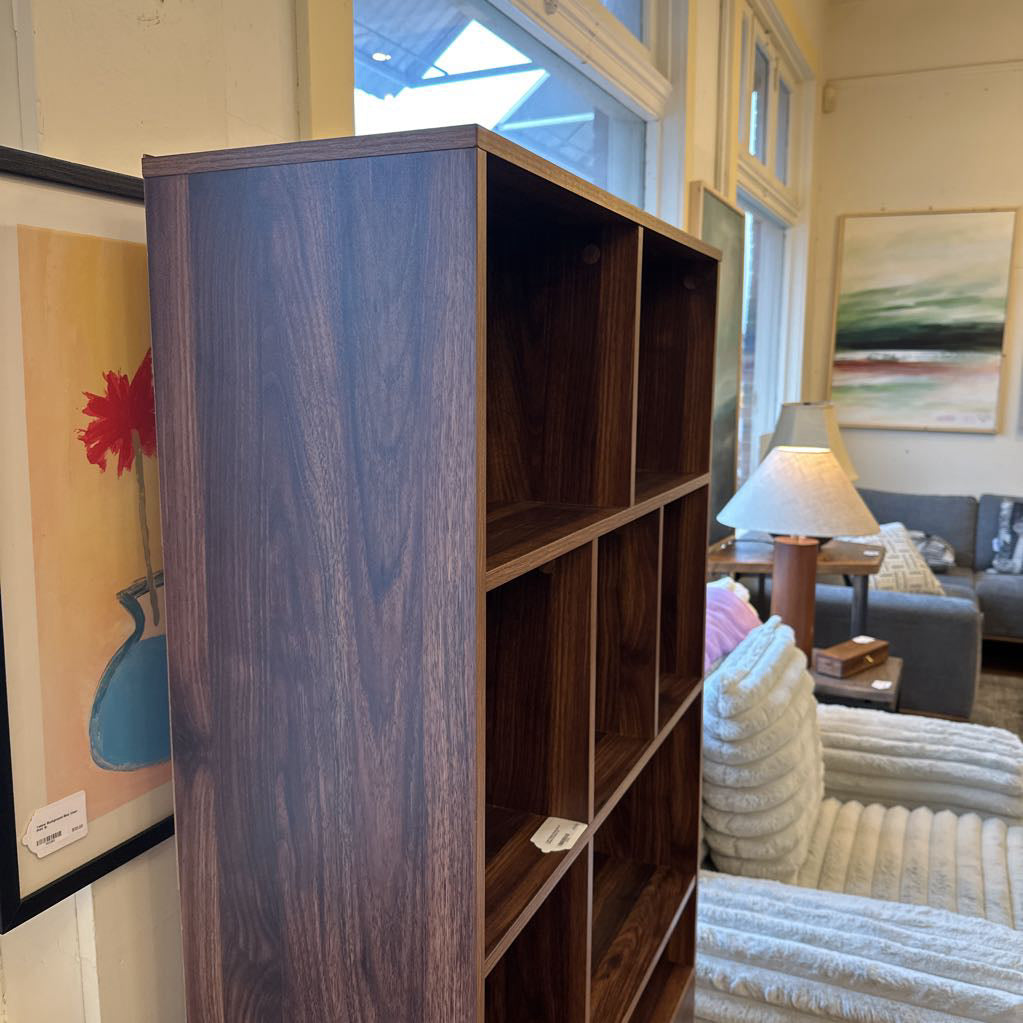 Wooden bookshelf in a living room with furniture and decor.