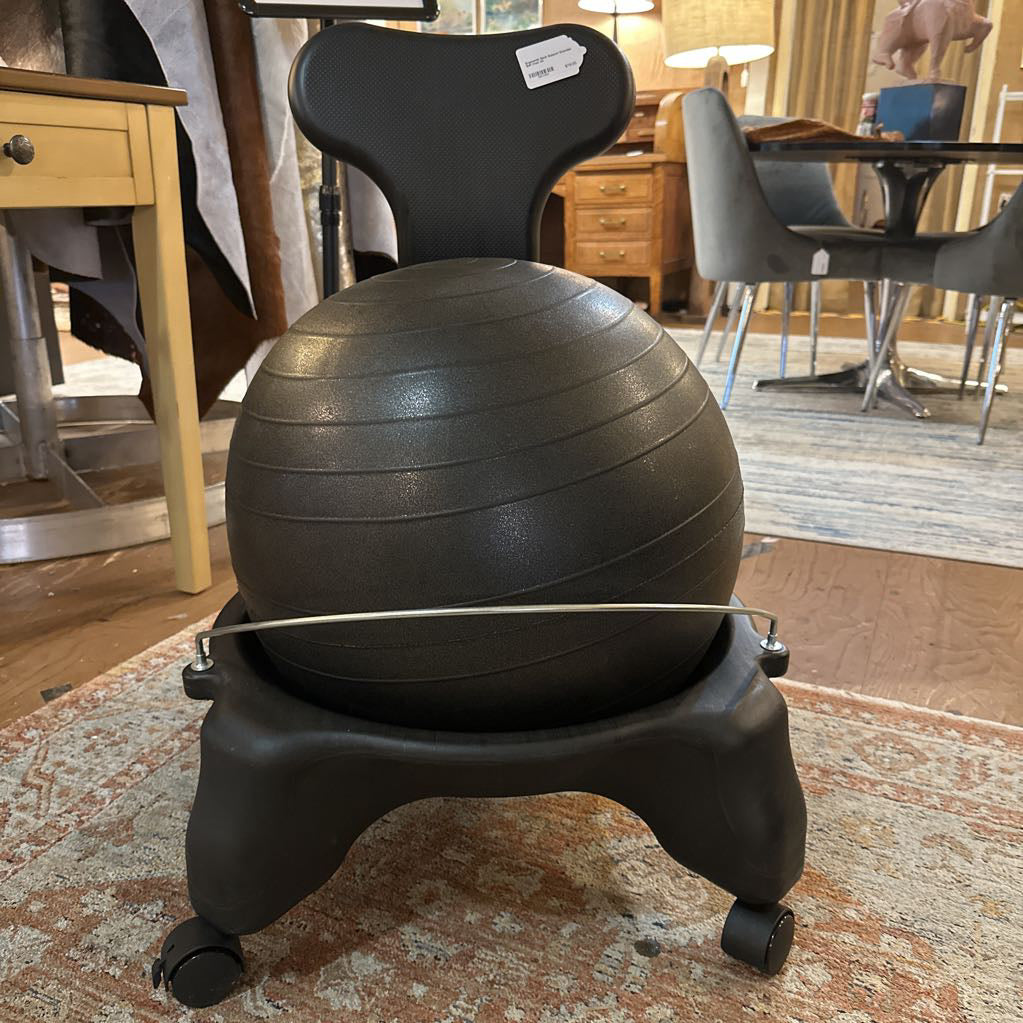 Black exercise ball chair in a room with furniture and decor.