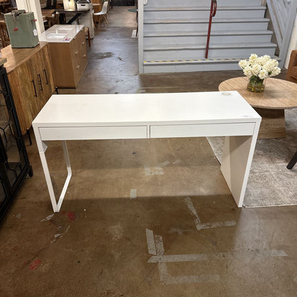 White desk in a room with wooden floor and furniture