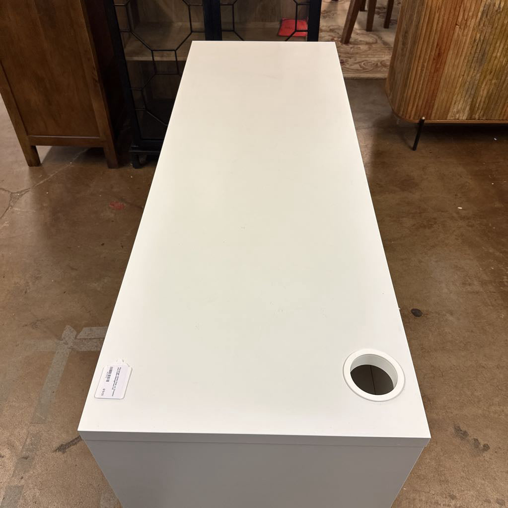 White rectangular table with a circular hole on a brown floor.