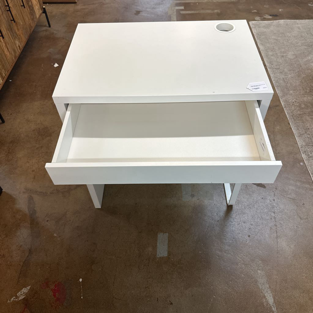 White desk with an open drawer on a concrete floor