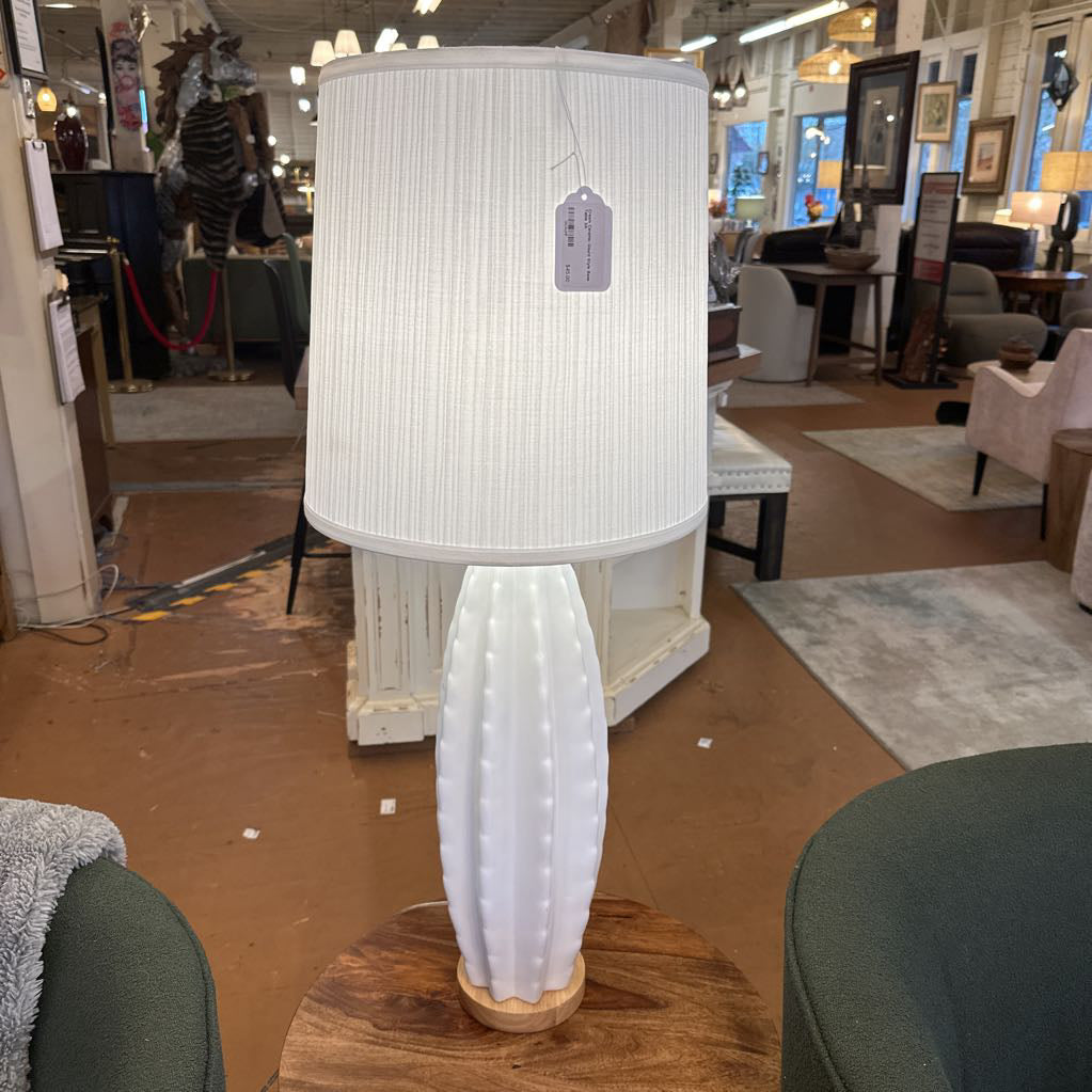 White lamp with a textured shade on a wooden table in a store setting