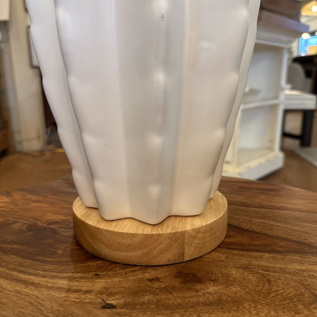 White ceramic vase on a wooden base with a blurred indoor background