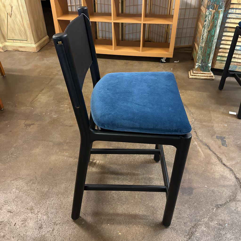 Black chair with a blue cushion on a concrete floor.