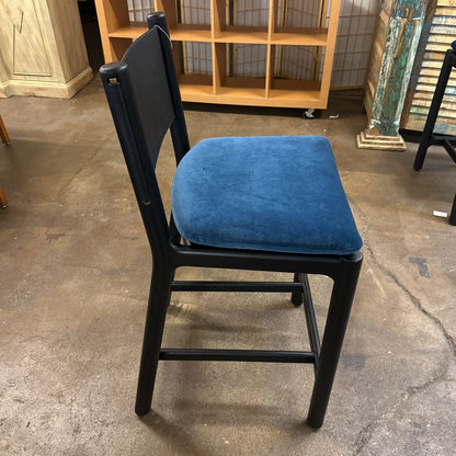 Black chair with a blue cushion on a concrete floor.
