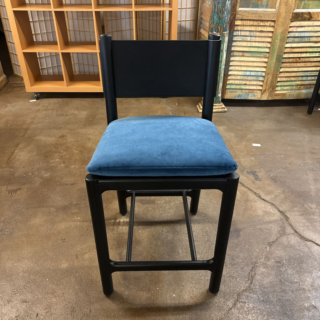 Chair with blue cushion and black frame on a concrete floor.