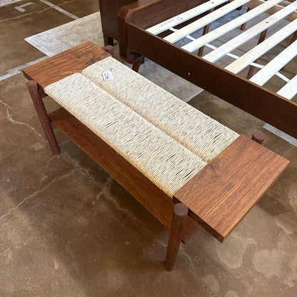 Wooden bench with woven seat on a stone floor