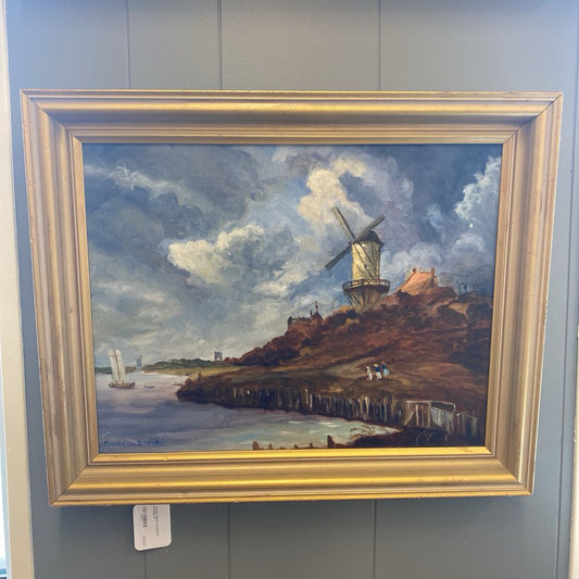 Painting of a windmill on a hill with a gold frame, displayed on a gray wall.