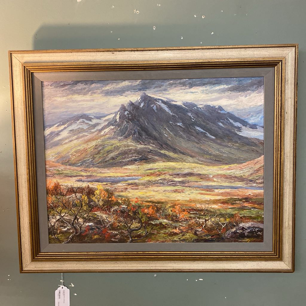 Framed painting of a mountain landscape on a gray wall