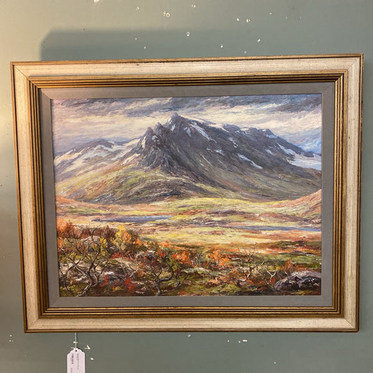 Framed painting of a mountain landscape on a gray wall