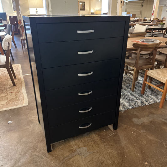 Black dresser with silver handles in a room with chairs and tables